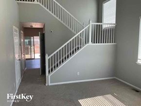 Commerce City house for rent - A staircase with a white railing and a beige carpeted floor.