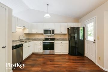 Columbus house for rent - a kitchen with white cabinets and black appliances