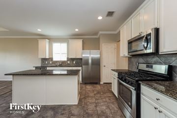 Converse house for rent - A kitchen with a black counter top and a stainless steel refrigerator.