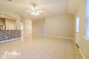 Baytown house for rent - A spacious room with a stone fireplace and a ceiling fan.