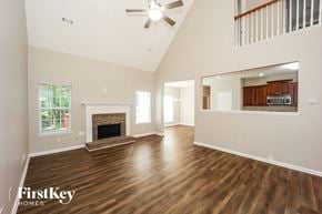 Fayetteville house for rent - an empty living room with a fireplace and a ceiling fan