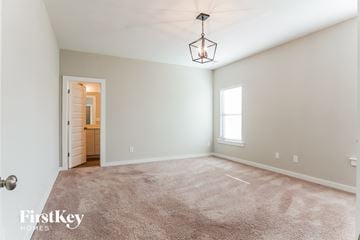 Jasper house for rent - a spacious living room with carpet and a light fixture