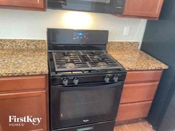 Thornton house for rent - A black stove top oven with four burners and a glass door is in a kitchen.