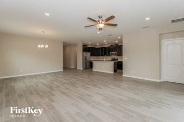 Jacksonville house for rent - A spacious room with a fan and a kitchen in the background.