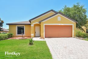 Deltona house for rent - A yellow house with a garage door is for sale by FirstKey Homes.