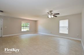 Deltona house for rent - A spacious room with a ceiling fan and two windows.