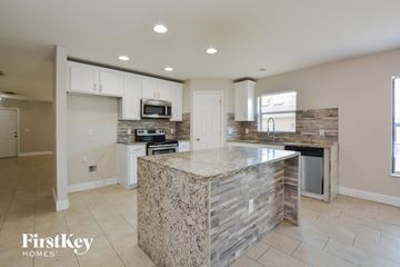 Deltona house for rent - A kitchen with a granite counter top and a stone backsplash.