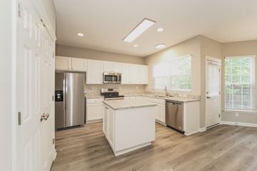 Charlotte house for rent - A kitchen with white cabinets and a wooden floor.