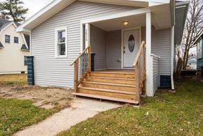 Lansing apartment for rent - a white house with a wooden porch and stairs