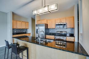 St. Paul apartment for rent - Kitchen with black countertops, bar seating, and stainless steel appliances