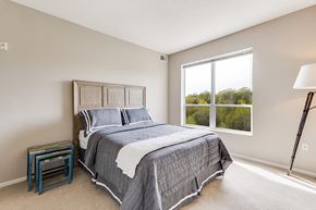 St. Paul apartment for rent - Bed with gray covers and pillows, a night stand, a lamp, and a window in a bedroom