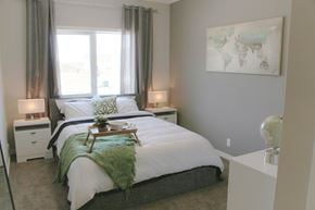 Saskatoon apartment for rent - A bedroom with a large bed and a painting on the wall.