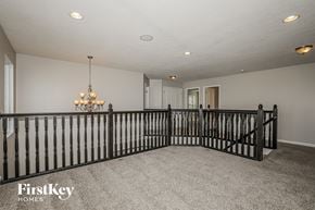 Avon house for rent - A spacious room with a chandelier and a black railing.