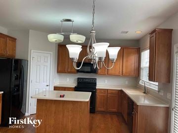 Charlotte house for rent - a kitchen with wooden cabinets and a chandelier