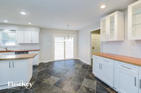 Archdale house for rent - A kitchen with white cabinets and a wooden counter top.