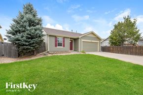 Lochbuie house for rent - A house with a green lawn and a tree in front of it.