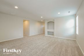 Lochbuie house for rent - A spacious empty room with a carpet floor and a fireplace.