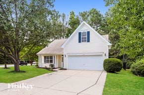 Raleigh house for rent - A white house with a garage is surrounded by greenery.