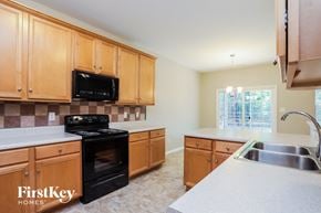 Raleigh house for rent - A kitchen with wooden cabinets and a black stove top oven.