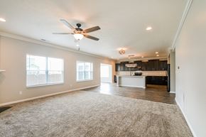 Fortville house for rent - an empty living room with a ceiling fan and a kitchen