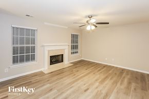 Harrisburg house for rent - A spacious room with a fireplace and a ceiling fan.