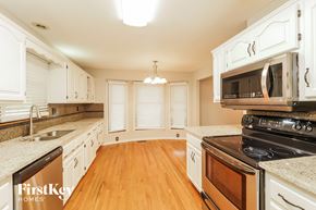 Kansas City house for rent - a kitchen with white cabinets and appliances and a wood floor
