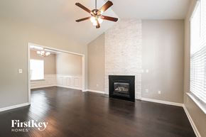 Holly Springs house for rent - A living room with a fireplace and a ceiling fan.