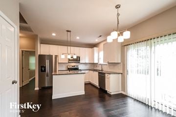 Holly Springs house for rent - A modern kitchen with a stainless steel refrigerator and white cabinets.