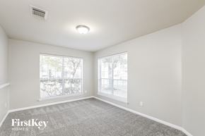 Tomball house for rent - A spacious room with a carpeted floor and two windows.