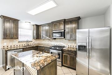 Tomball house for rent - A kitchen with a stove top oven and a refrigerator.