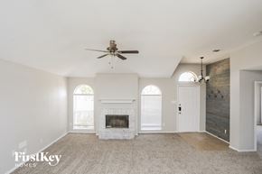Mesquite house for rent - an empty living room with a fireplace and a ceiling fan