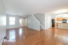 Thornton house for rent - A spacious living room with wooden floors and a staircase leading to the upper level.