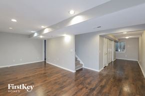 Thornton house for rent - A spacious room with wooden floors and a staircase leading to another room.