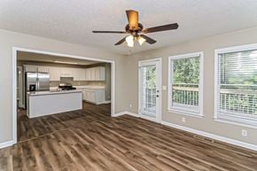 Powder Springs house for rent - an empty living room with a ceiling fan and a kitchen
