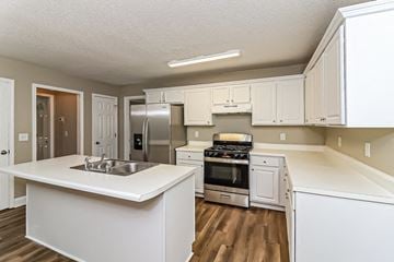 Powder Springs house for rent - an open kitchen with white cabinets and appliances and a sink