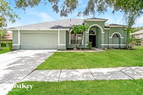 Valrico house for rent - a green house with a lawn and a driveway