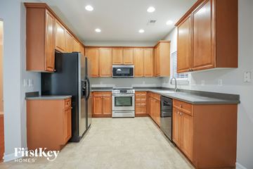 Summerville house for rent - A kitchen with wooden cabinets and a black refrigerator.