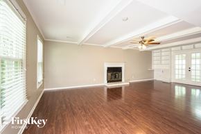 Greensboro house for rent - A spacious room with a fireplace and wooden floors.