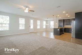 St Johns house for rent - an empty living room with a kitchen and a ceiling fan