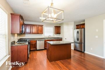 Dallas house for rent - a kitchen with wooden cabinets and stainless steel appliances and a chandelier