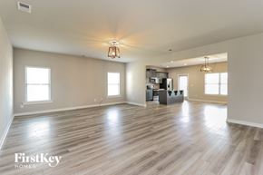 Jemison house for rent - A spacious room with wooden floors and a kitchen area in the background.