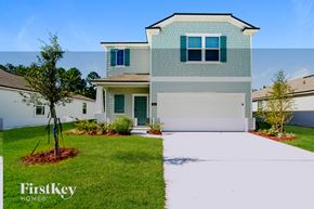 St Augustine house for rent - A modern house with a white garage door and a tree in front.