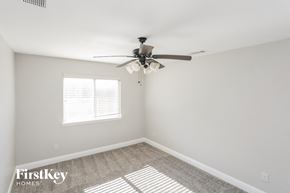 Waxahachie house for rent - a bedroom with white walls and a ceiling fan