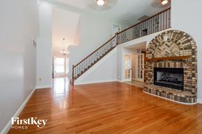Lake St. Louis house for rent - A large open living room with a stone fireplace and a staircase.
