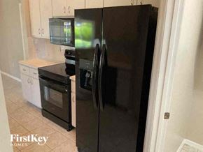 Cape Coral house for rent - a kitchen with a black refrigerator and a stove