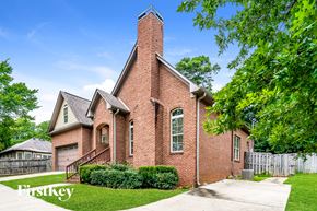 Hoover house for rent - A brick house with a chimney and a fence in front.