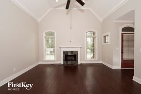 Hoover house for rent - A spacious room with a fireplace and a ceiling fan.
