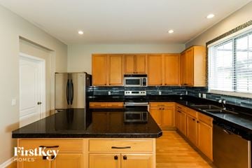 Riverview house for rent - A kitchen with wooden cabinets and black countertops.