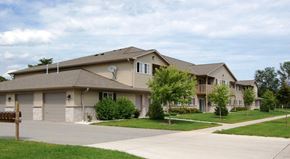 Manitowoc apartment for rent - a beige house with a driveway and trees