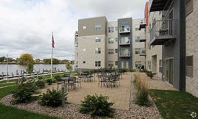 Oshkosh apartment for rent - an apartment building with tables and chairs near the water